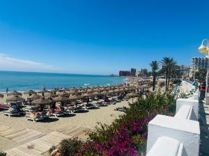 贝纳尔马德纳Luxury beachfront apartment in Benalmadena Costa的海滩上设有遮阳伞和椅子,还有大海