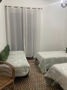 La Puerta de SeguraLa magnolia的一间设有两张床、椅子和窗帘的房间