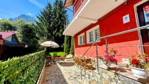 布什泰尼Valea Albă View - SELF CHECK-IN的红色的房子,配有椅子和雨伞