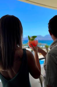 阿基欧斯尼古拉斯Faedra Beach的窗户前拿着饮料的女人