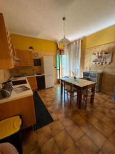 Piossascoking's house的一间带桌子的厨房和一间带黄色墙壁的厨房