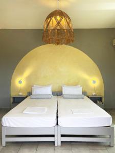 梅加斯·亚洛斯-奈特斯Agnadi Syros Beachfront Studios & Rooms的配有吊灯的客房内的两张床