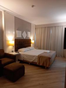 瓜鲁柳斯International Airport Flat - Guarulhos quarto 1267的配有一张床和一把椅子的酒店客房