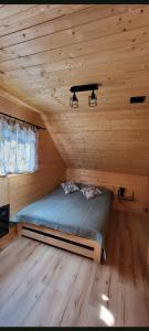 DziemianyDomek w sercu Kaszub的小屋内的一张床位,设有木制天花板