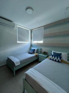 普拉亚布兰卡Playa Blanca Beach Rentals的一间卧室设有两张床和两个窗户。
