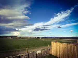 瑟索Glengolly Getaways的一片有栅栏的田野和一片云天的蓝色天空