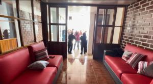 瓦拉斯Casa Hospedaje “YURAQ WASI”的客厅配有红色沙发,客人步行可至门口