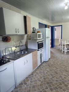 拉热斯Casa Amarela的厨房配有白色家电和桌椅