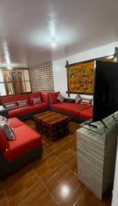 瓦拉斯Casa Hospedaje “YURAQ WASI”的客厅配有红色沙发和电视
