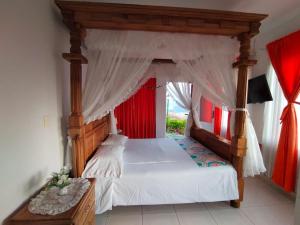 佩雷拉芬卡梦幻别墅的一间卧室配有一张带红色窗帘的天蓬床