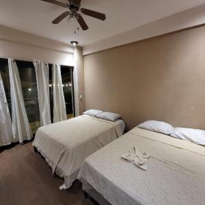 El CongoRestaurante y Hostal Romayor的一间卧室配有两张床和吊扇