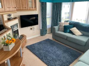 GreatstoneRomney Sands holiday home的客厅配有蓝色的沙发和电视
