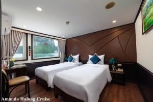 下龙湾Amanda Legend Cruise Ha Long Bay的酒店客房设有两张床、一张书桌和窗户。