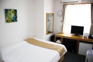Iidamachiビジネスホテル 山手INN的一间卧室配有一张床和一张带电脑的书桌