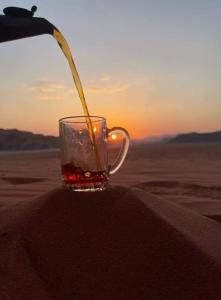 瓦迪拉姆Wadi Rum Sights Camp的正在沙漠里把饮料倒进玻璃杯里