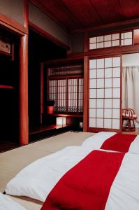 大阪Teradaya Osaka Ryokan 150m2 寺田屋大阪旅館 your own property sweet home in Osaka的窗户客房内的一张红色和白色的床