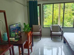 万荣Vang Vieng Champa Hotel的一间卧室配有桌子、椅子和窗户