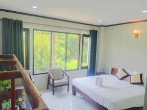 万荣Vang Vieng Champa Hotel的一间卧室配有一张床、一把椅子和窗户。