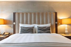釜山釜山乐天酒店的一间卧室配有一张大床和两盏灯