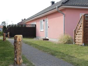 普鲁滕Boddensurfer 3a Comfortable holiday residence的粉红色的房子,设有大门和栅栏