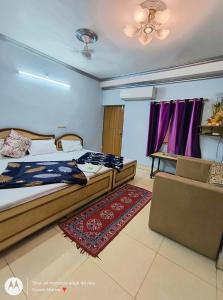 阿格拉Hotel Swarajya Palace的一间卧室配有两张床、一张沙发和紫色窗帘