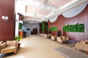 马马亚Hotel Ambasador Mamaia的大堂的墙壁上摆放着长沙发和植物