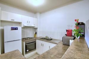 阿德莱德Acgated Parking North Adelaide Balcony Suite的厨房配有白色橱柜和白色冰箱。