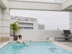 那霸Okinawa EXES Naha的躺在建筑物游泳池中的女人