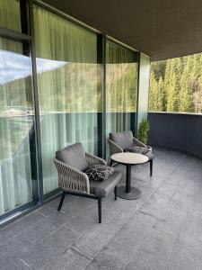 布克维SAVOIE Apartments Bukovel的阳台配有两把椅子和一张桌子,阳台设有窗户