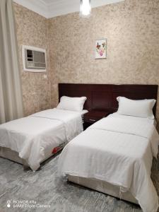 巴勒如拉斯فندق وشقق ليالي الاحلام للشقق المخدومه的配有白色床单的酒店客房内的两张床