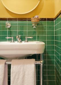 佛罗伦萨赫米缇吉酒店的一间带水槽和绿色瓷砖墙壁的浴室