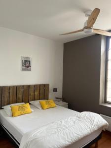 圣马丹德雷Jolie location contemporaine dans Saint Martin de Ré的一间卧室配有一张带黄色枕头的床和吊扇。