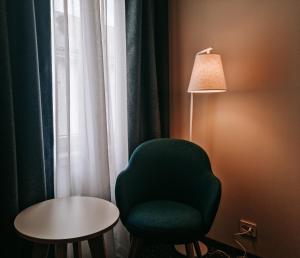 奥勒松Hotel Noreg的一间设有绿椅、台灯和桌子的房间