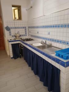 普罗斯西托角Casa Lido degli Angeli a 120m dal mare的蓝色和白色瓷砖厨房,配有水槽