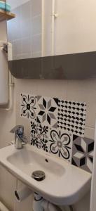 叙雷纳Cosy Appartement Paris Ouest的墙上设有带鲜花水槽的浴室