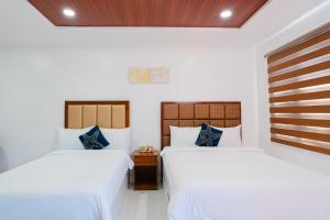 CabanganQ Beach Resort的白色墙壁客房的两张床