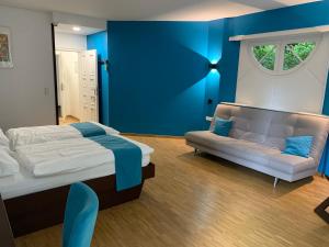 施韦特Haus Villigst - Tagungsstätte der EKvW的卧室拥有蓝色的墙壁,配有一张床和一张沙发