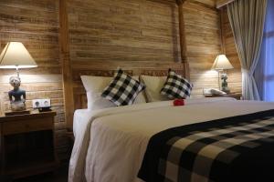 Bangli巴厘岛乌玛传统生态旅馆的一间卧室配有一张大床和两盏灯。