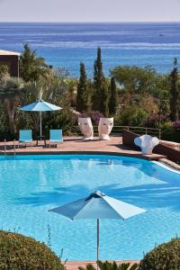 林都斯Aquagrand Exclusive Deluxe Resort Lindos - Adults only的一个带遮阳伞和椅子的游泳池以及大海