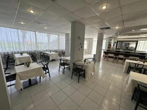 塞奥洛戈斯Ayit Hotel的一间设有白色桌椅和钢琴的餐厅