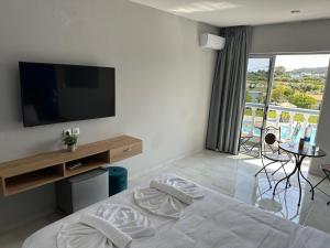 塞奥洛戈斯Ayit Hotel的一间卧室设有一张带电视的床和一个阳台。