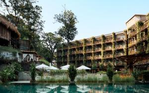 芭东海滩Dinso Resort & Villas Phuket, Vignette Collection, an IHG Hotel的游泳池前带遮阳伞的大型建筑