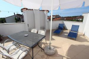 罗维尼Rooms and Apartment Luana的阳台配有桌椅和遮阳伞