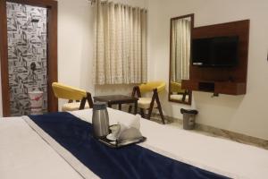 范兰德凡Guru Kripa sadan的酒店客房设有一张带桌子的床和一台电视。