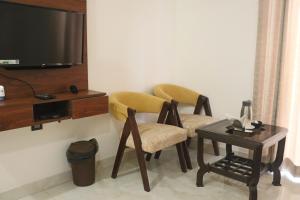 范兰德凡Guru Kripa sadan的一间设有两把椅子、一张桌子和一台电视的房间