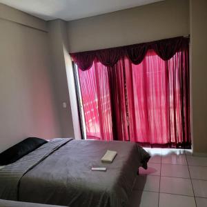 圣安娜Restaurante y Hostal Romayor的一间卧室配有床和红色窗帘的窗户