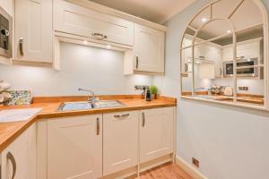 托基Appartement in Torquay mit Terrasse, Grill und Garten的厨房配有白色橱柜和水槽