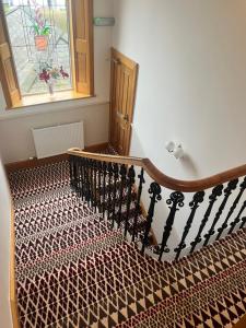 卡诺斯蒂Morven Guest House Carnoustie的带有图案地毯和窗户的楼梯