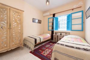 西迪·布·赛义德Coup de cœur à Sidi Bou Said的一间卧室设有两张床、一个橱柜和一个窗口。