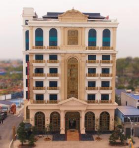 海防Nguyễn Đức DC Hotel & Spa的一座大型白色建筑,设有金色大门